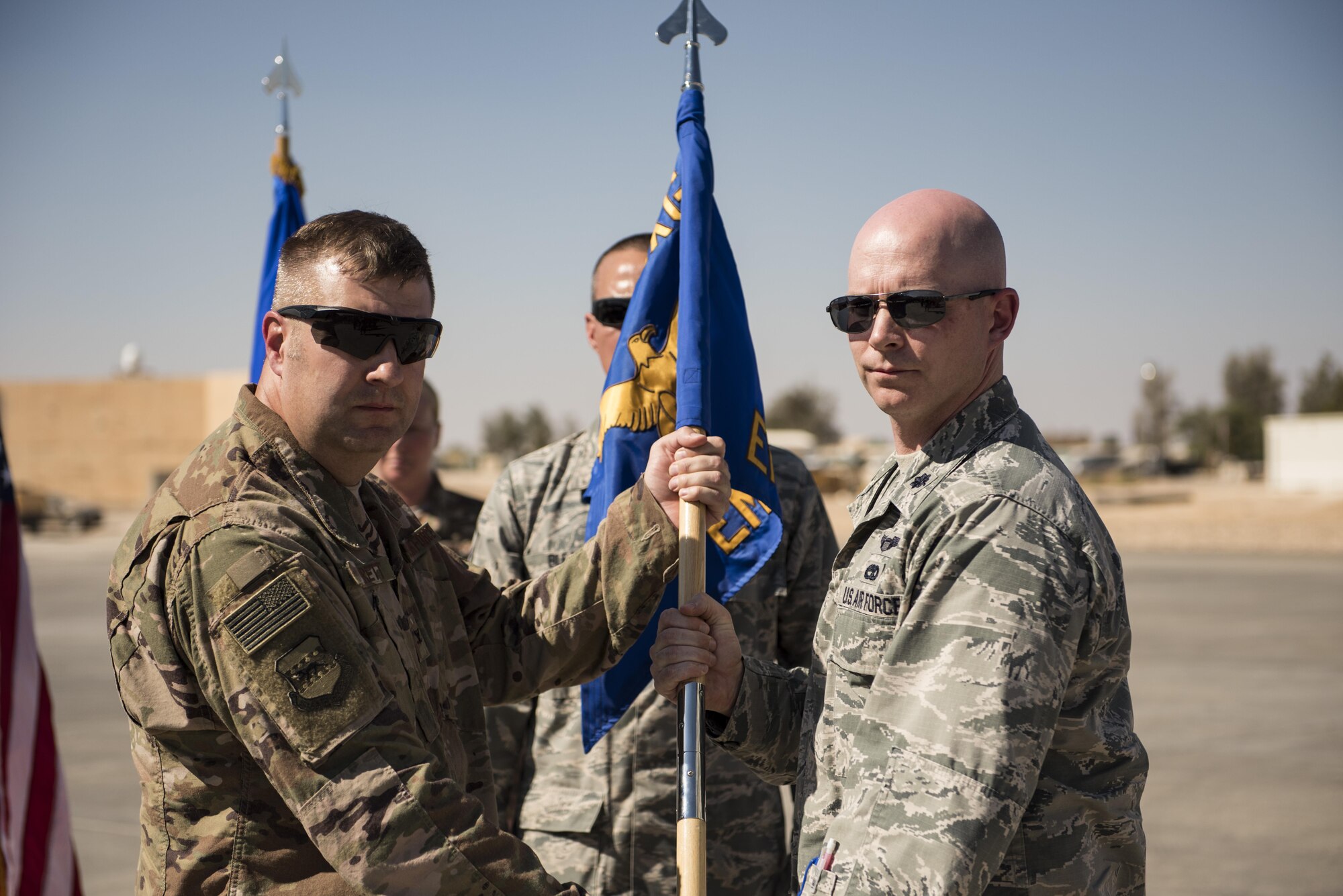 Col Shane Barrett, 332nd Expeditionary Maintenance Group commander, hands over the guidon to Lt. Col. Scott May during a change of command ceremony October 6, 2017 in Southwest Asia. Lt. Col. May assumed command of the 332nd Expeditionary Maintenance Squadron. (U.S. air Force photo by Senior Airman Joshua Kleinholz)