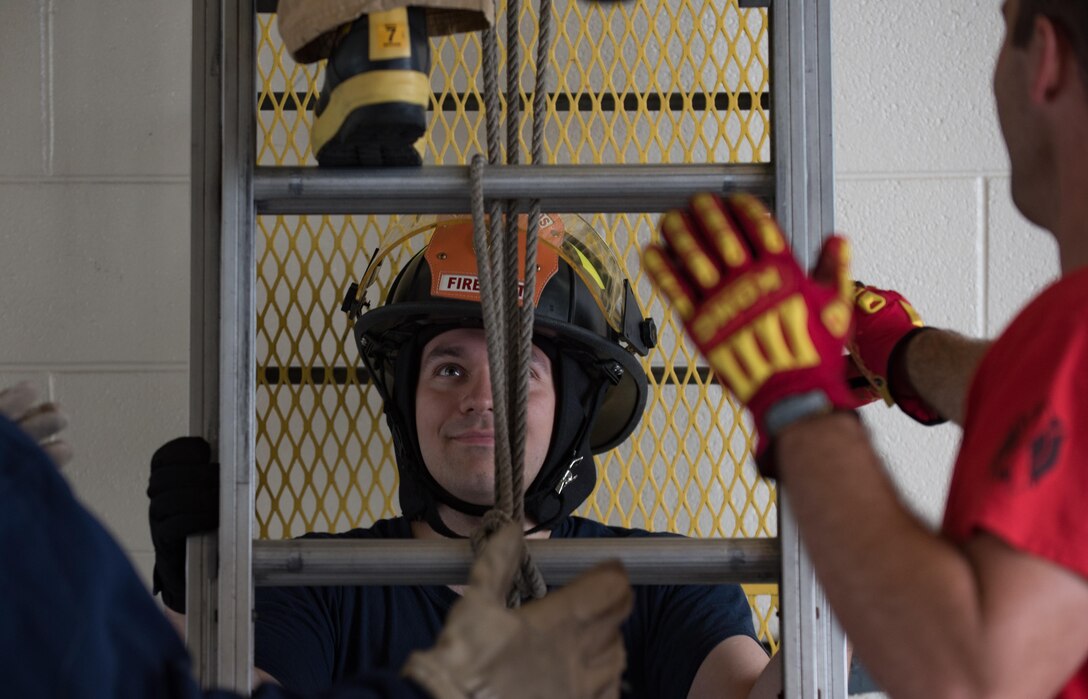 U.S. Air Force Airman 1st Class Zachariah Christenson, Firefighter Combat Challenge safety monitor, stabilizes a ladder climb obstacle during the challenge at Joint Base Langley-Eustis, Va., Oct. 13, 2017.