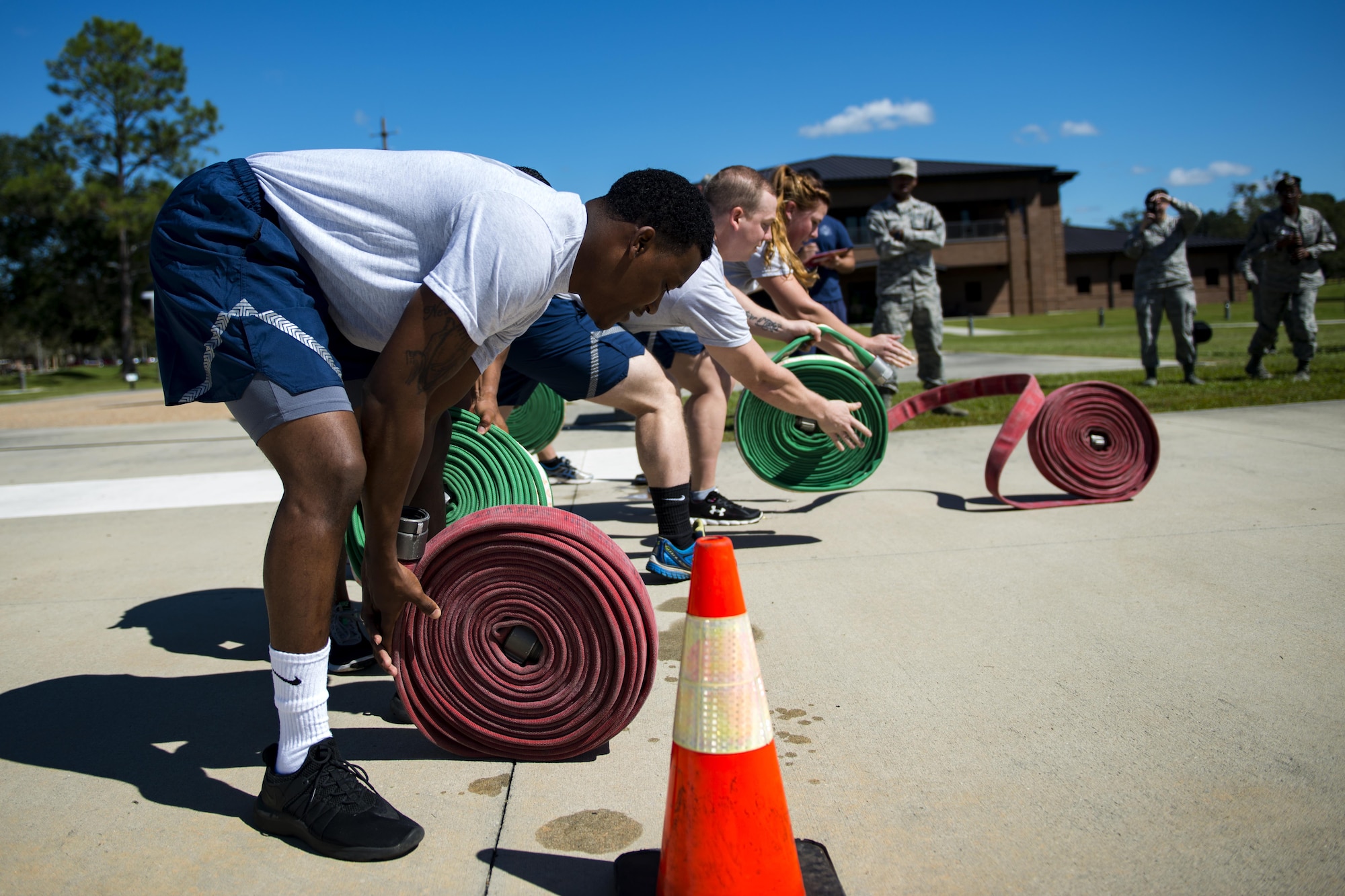 Airmen assigned to the 23d Security Forces Squadron unroll firehoses during the 2017 Fire Prevention Week Fire Muster, Oct. 13, 2017, at Moody Air Force Base, Ga. The 23d Civil Engineer Squadron fire department designed the muster to allow teams of Airmen to compete in several events, ranging from a hose roll to a fire truck pull. Event organizers wanted Airmen to experience being a firefighter in a way that got people active. (U.S. Air Force photo by Airman 1st Class Erick Requadt)