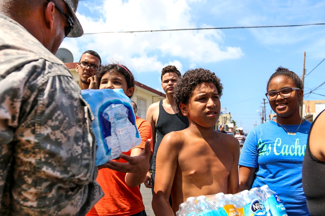 A soldier gives a case of water to a resident in Puerto Rico.
