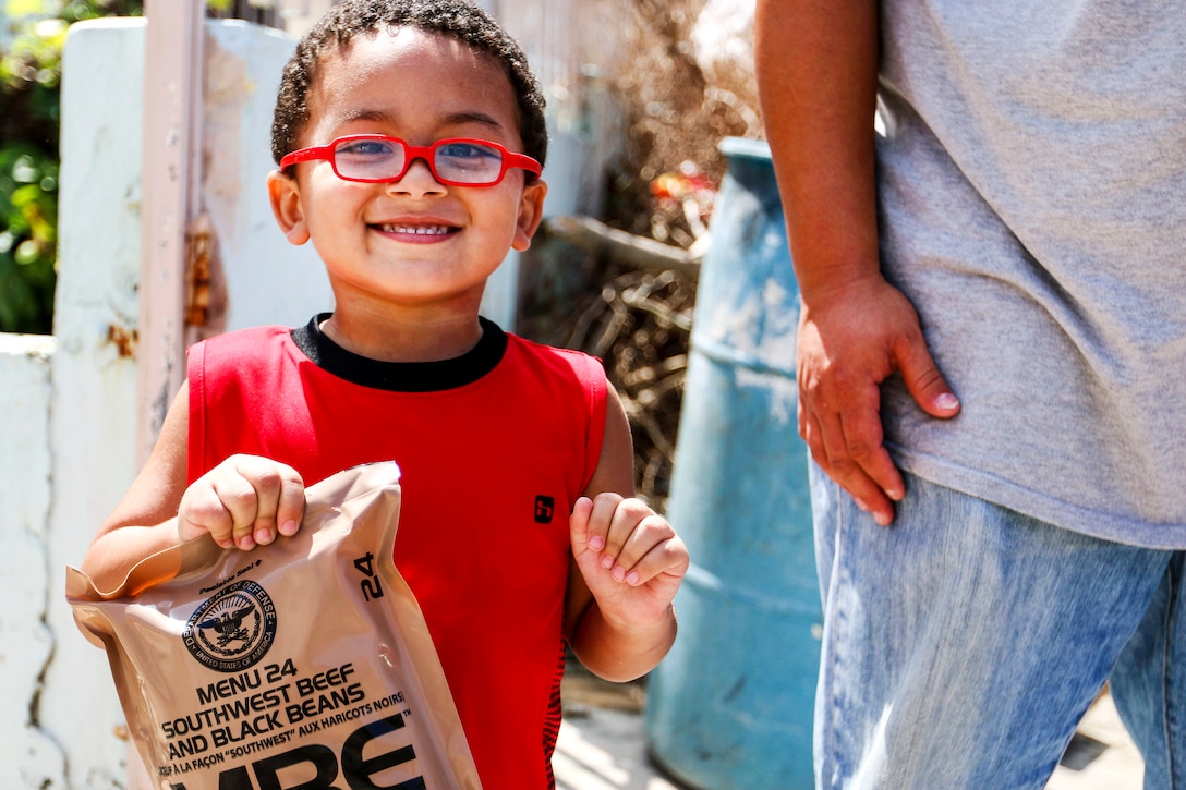 A boy smiles after receiving a packaged meal from soldiers in Puerto Rico.