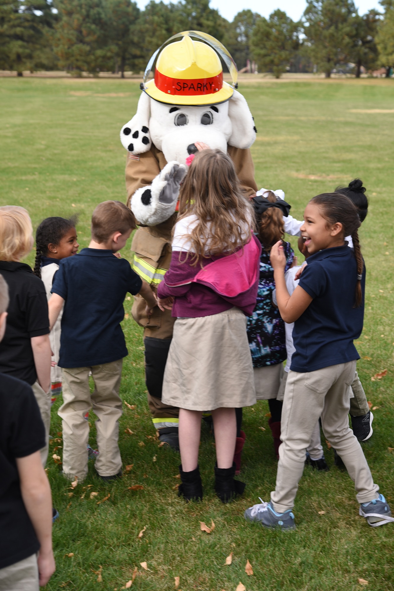 Sparky, 21st Civil Engineer Fire Department mascot, greets children behind the R.P. Lee youth center on Peterson Air Force Base, Colorado Oct. 11, 2017. He participated in a fire drill and evacuated the building with the children. (U.S. Air Force photo by Robb Lingley)