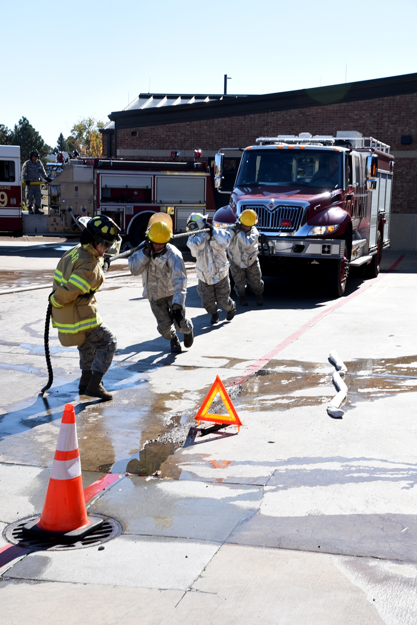 Four Airmen pull a fire truck to safety during the Fire Muster competition at the 21st Civil Engineer fire station at Peterson Air Force Base, Colorado, Oct. 13, 2017. Three teams of four Airmen competed in the event. (U.S. Air Force photo by Robb Lingley)