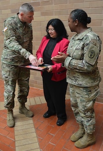 Brooke Army Medical Center commanding general Brig. Gen. Jeffrey Johnson and Warrior Transition Battalion Command Sgt. Maj. Karen Hinckson present Sylvia De Leon (center) a token of appreciation Oct. 5 at the BAMC Hispanic Heritage Month observance. De Leon, a professor at San Antonio College, was the guest speaker at the event.