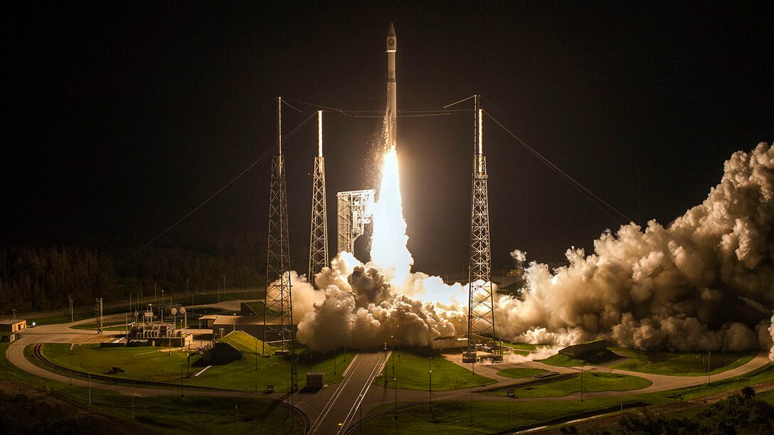 A rocket takes off from a launchpad at night.