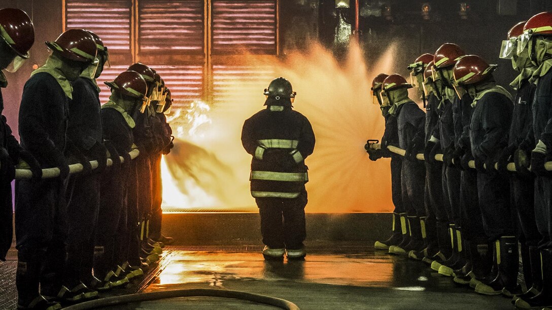 Sailors train to fight fires on a ship.