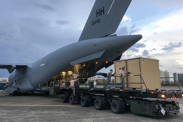Guardsmen unload equipment from a large airplane.