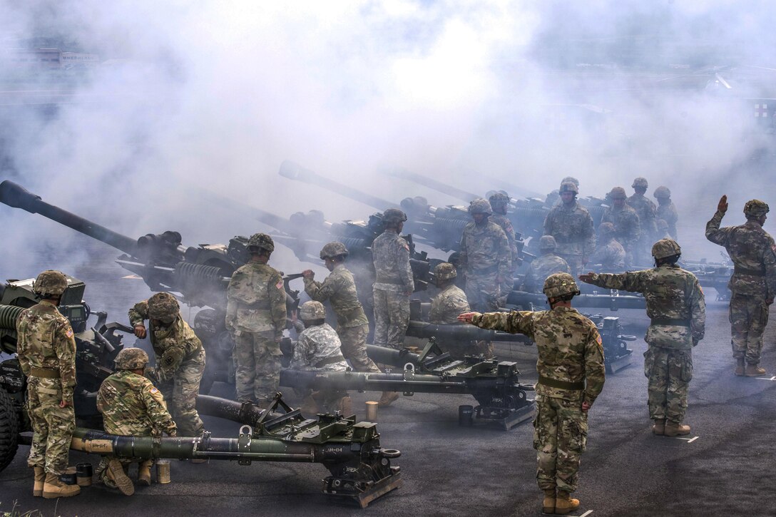 Soldiers line up and fire large weapons.