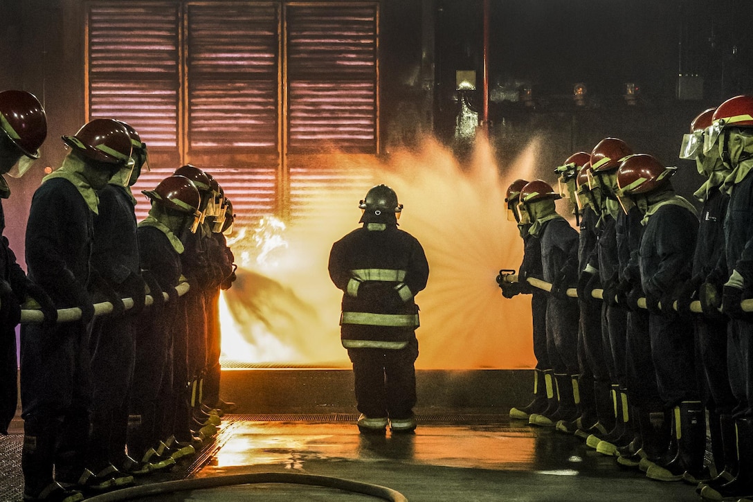 Sailors train to fight fires on a ship.