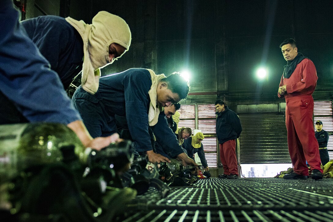 Sailors aboard the amphibious dock landing ship USS Ashland to prepare their self-contained breathing apparatus.