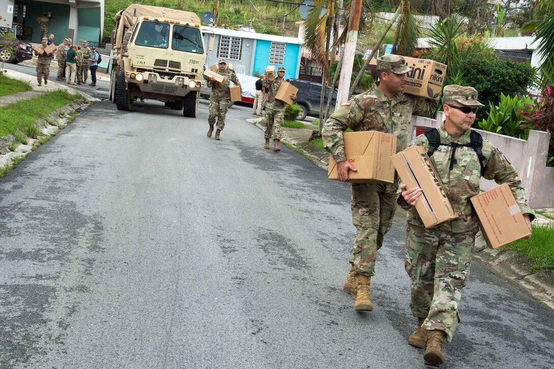 Soldiers and the Puerto Rico National Guardsmen deliver cases of water and shelf-stable meals to residents.