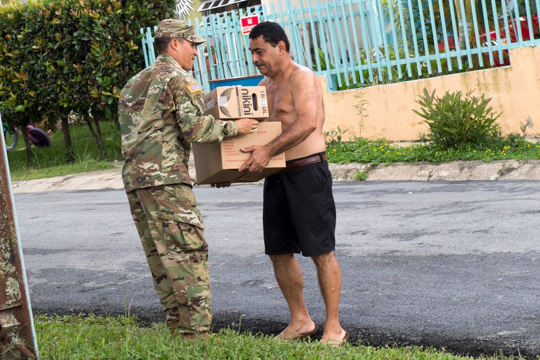 A soldier delivers cases of shelf-stable meals to a resident.
