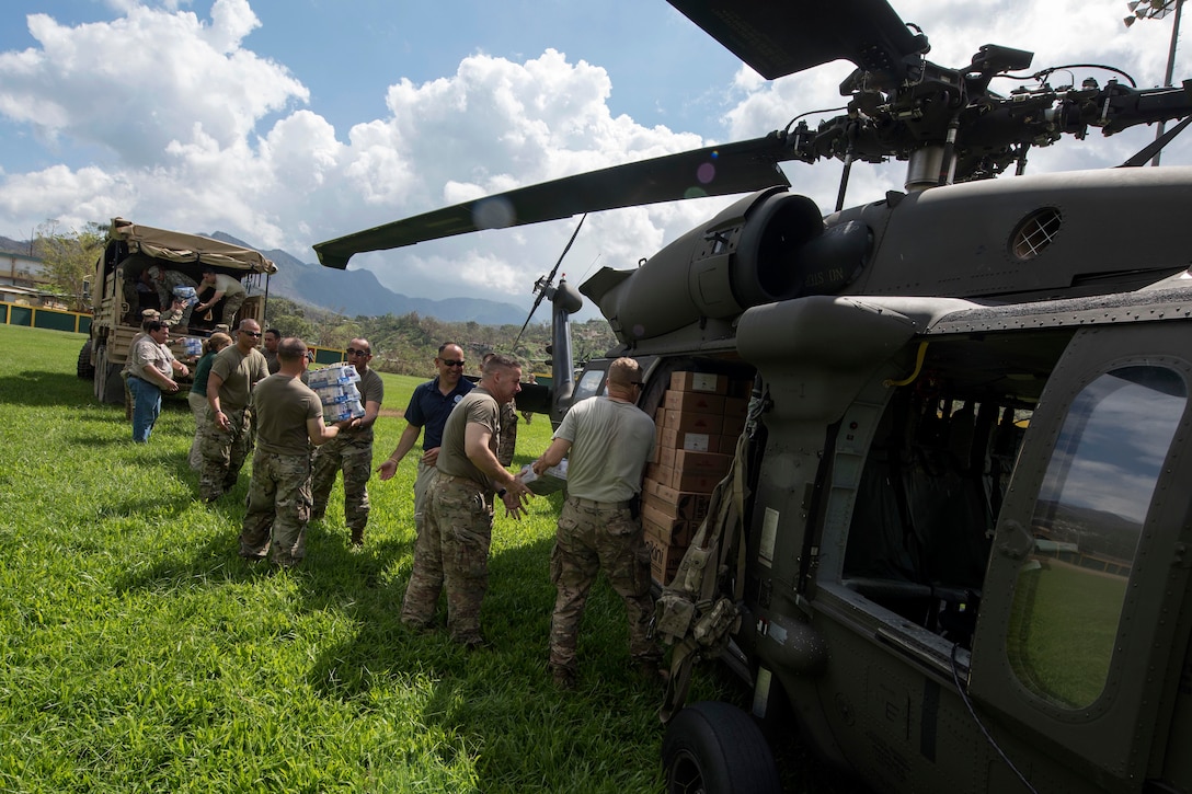 Army Lt. Gen. Jeff Buchanan and Puerto Rico Army National Guardsmen unload food, water and critical supplies from a UH-60 Black Hawk