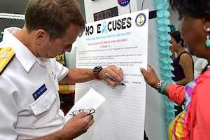 A Navy Admiral signs a board.