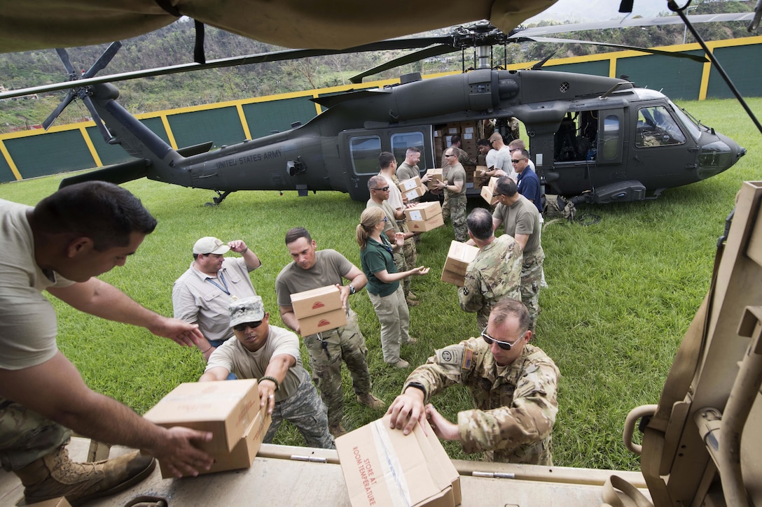 Puerto Rico Army National Guardsmen load food, water and critical supplies from a UH-60 Black Hawk helicopter onto a truck.