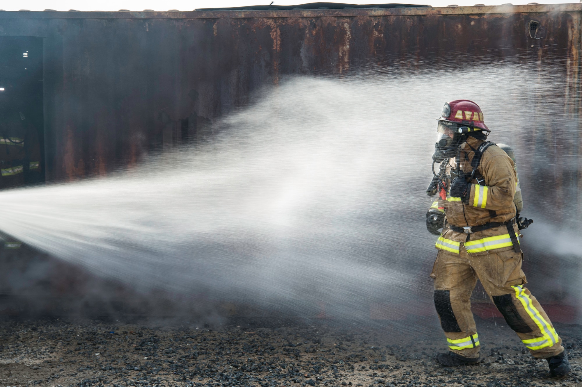 A fire fighter from the 386th Expeditionary Civil Engineer Squadron Fire Department is hosed down after exiting a live fire training facility at an undisclosed location in Southwest Asia, Oct. 20, 2017. The training was a coordinated effort with various units on base to ensure Airmen's safety was upheld and mission capability was not interrupted. (Air Force photo by Staff Sgt. William Banton)