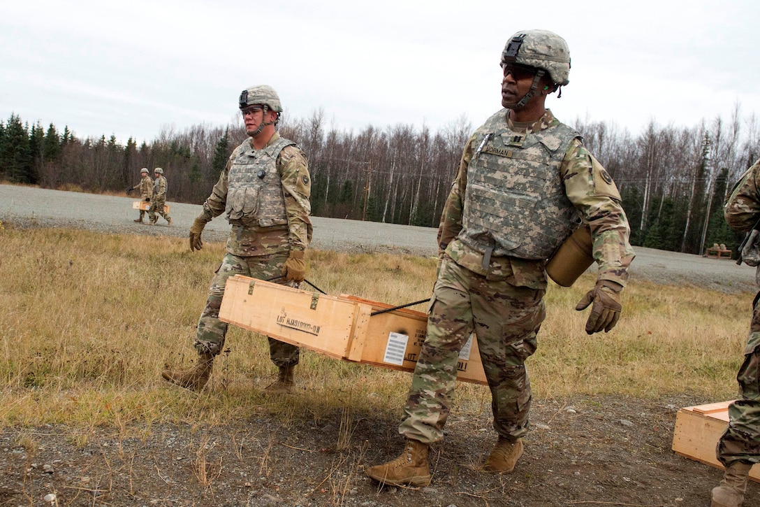 Soldiers carry a crate of AT4-CS light anti-armor rocket launchers to the firing line during live-fire training.