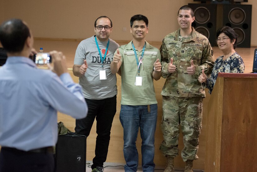 One soldier and three civilians pose together for a photo.