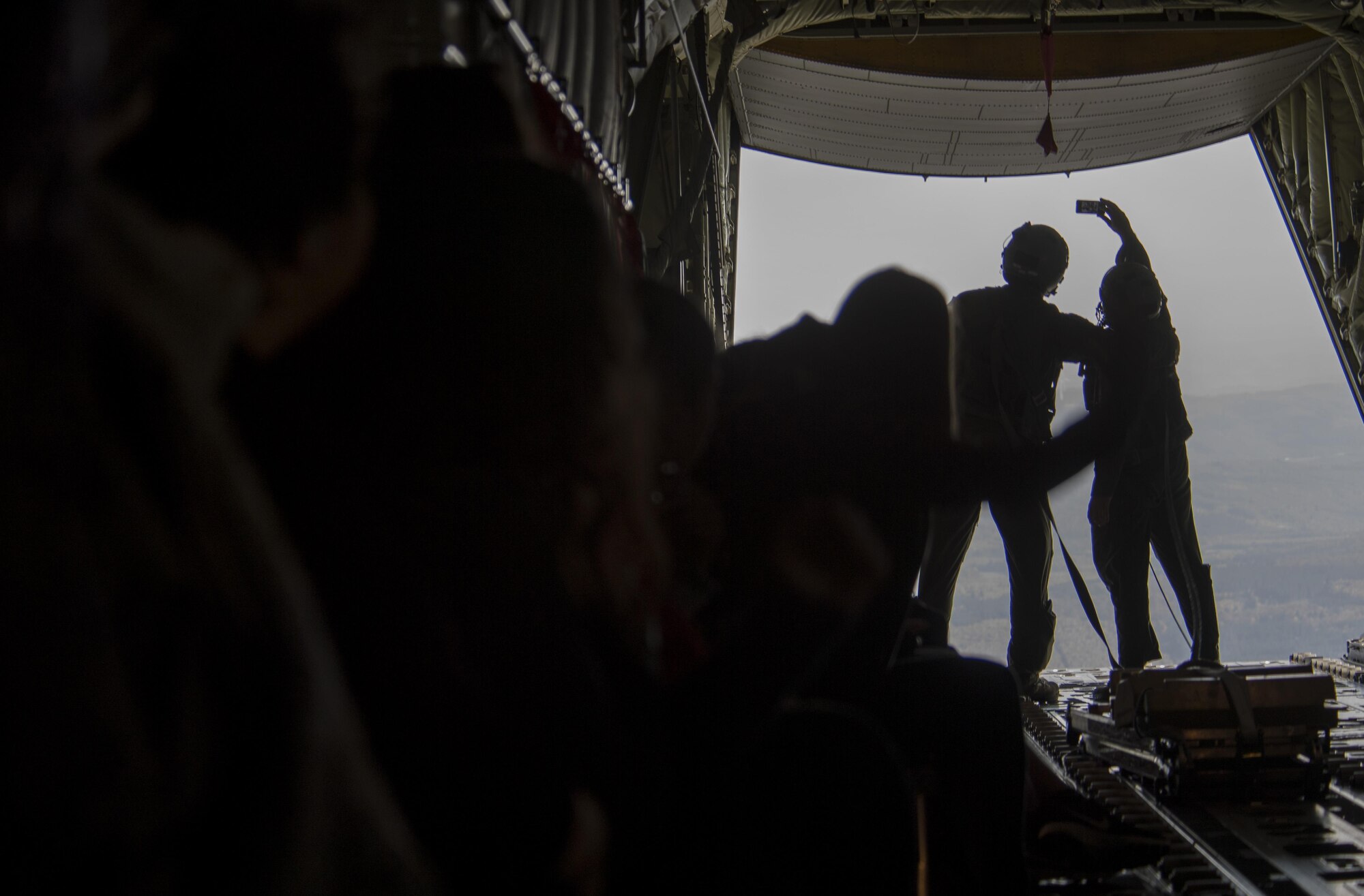 U.S. Air Force Tech. Sgt. Duane C. Jensen III (right) and Airman 1st Class Benjamin McElwain, both 37th Airlift Squadron loadmasters, take a selfie with a military spouse’s phone aboard a C-130J Super Hercules flying near Ramstein Air Base, Germany, Oct. 17, 2017. The Ramstein Airman and Family Readiness Center hosted their Heart Link program to provide information and networking opportunities to military spouses and included an incentive flight aboard the aircraft. (U.S. Air Force photo by Senior Airman Tryphena Mayhugh)