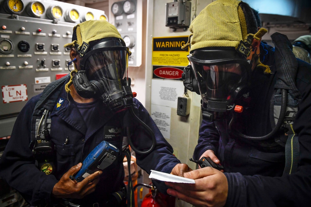 Sailors investigate a gas leak.