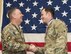 Lt. Gen. Brad Webb shaking hands with Tech. Sgt. Thomas Wojak with American flag in background.