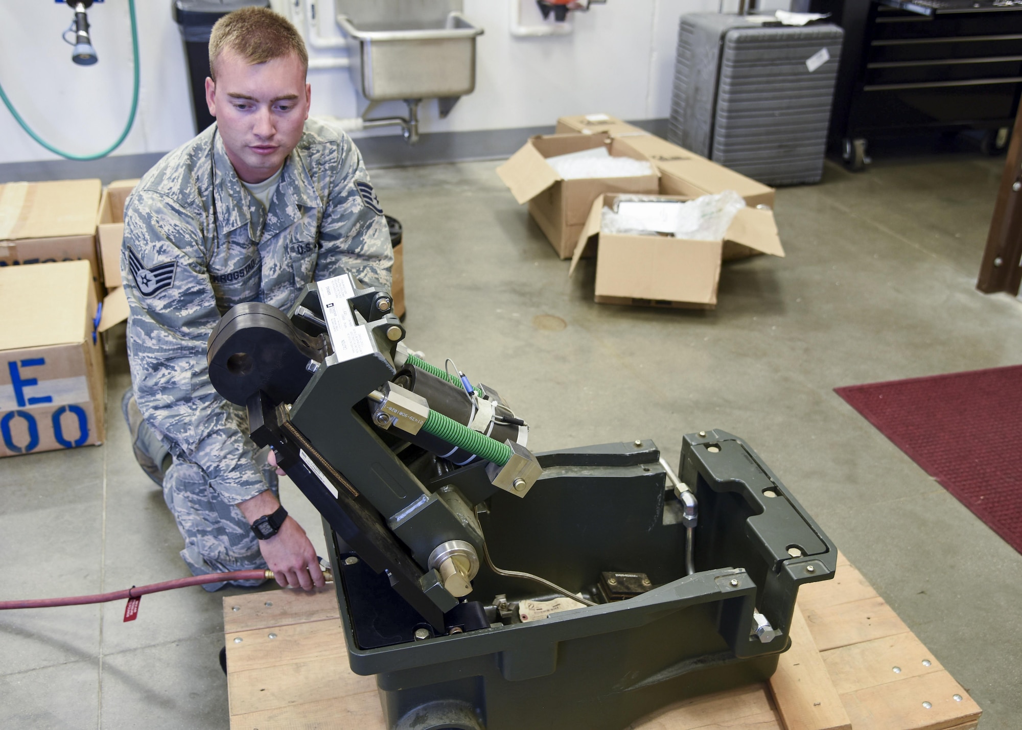 Staff Sgt. Scott Krogstad, 114th Civil Engineer power production specialist, demonstrates the functions of the BAK-14M retractable hook cable support system in the power production shop at Joe Foss Field, Sept. 9, 2017.