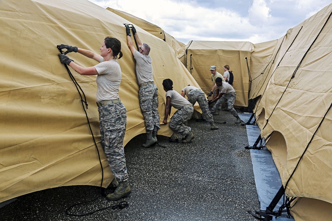 A group of guardsmen tie ropes to secure tents.