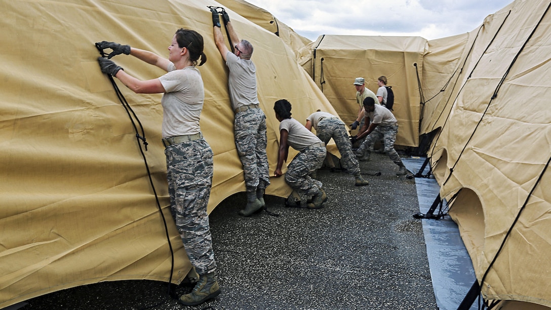 A group of guardsmen tie ropes to secure tents.