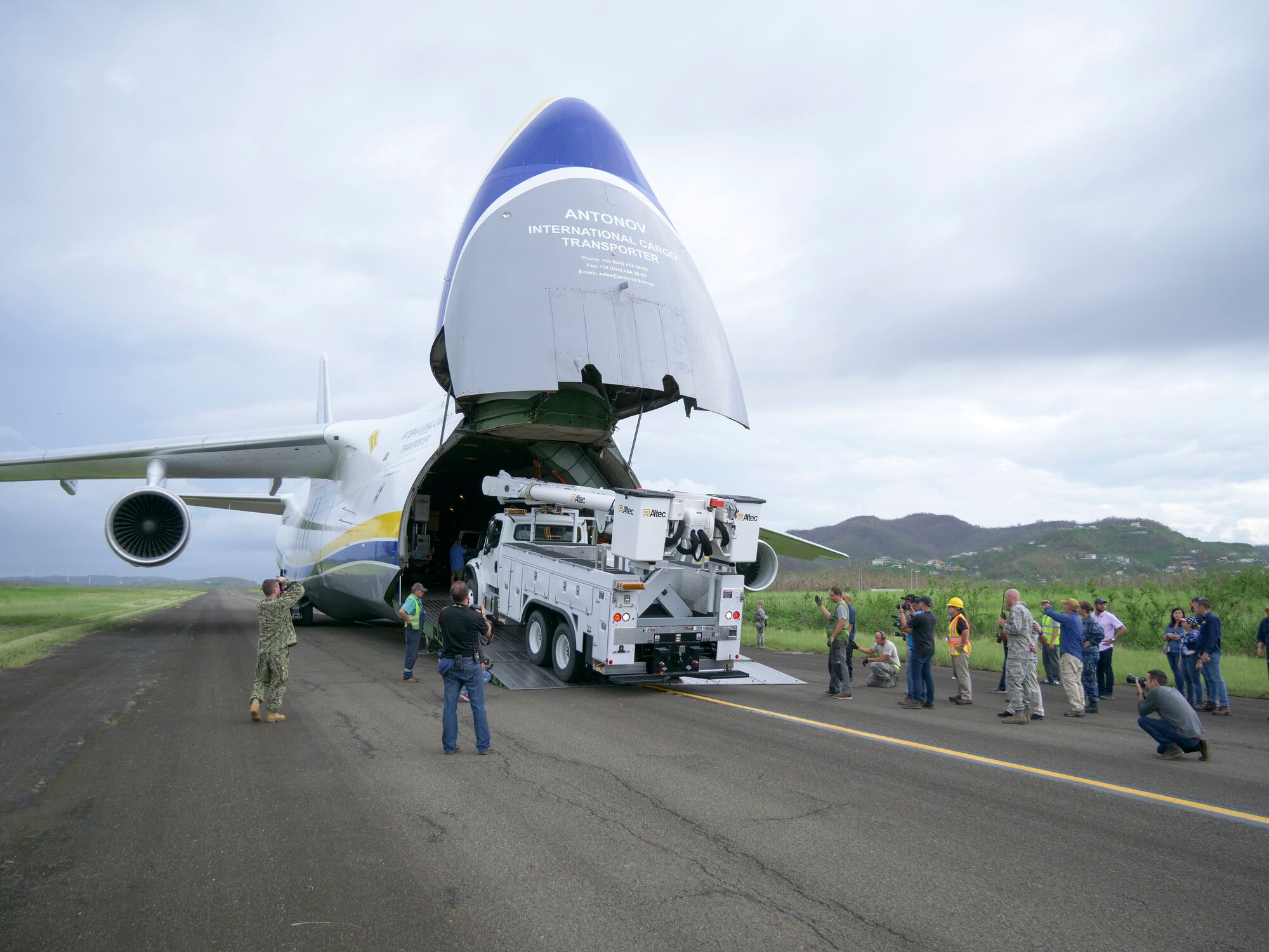 Members of the 821st Contingency Response Group help to offload line trucks from a Ukrainian Anatov 124-100m cargo transporter onto the tarmac of Jose Aponte De La Toore Airport in Ceiba, Puerto Rico, Oct. 11, 2017.