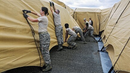 A group of guardsmen tie ropes to secure tents.