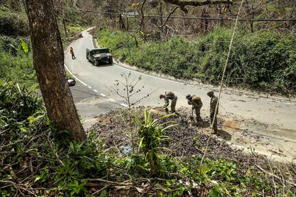U.S. Marines with Battalion Landing Team 2nd Battalion, 6th Marine Regiment, 26th Marine Expeditionary Unit (MEU), and Detachment 1, Landing Support Company, Combat Logistics Regiment 45, 4th Marine Logistics Group, shovel debris off of a roadway during road clearance operations in Ponce, Puerto Rico, Oct. 9, 2017.