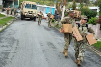 Soldiers and the Puerto Rico National Guardsmen deliver cases of water and shelf-stable meals to residents.