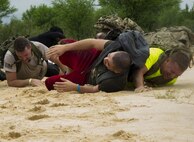 Participants in a ruck march challenge slink through a sand-filled volleyball court at Laughlin Air Force Base, Texas, Oct. 14, 2017.  The ruck, which started at Laughlin’s football field and continued throughout the base, was a 10-kilometer march which contained various challenges at various points along the route. (U.S. Air Force photo\Airman 1st Class Daniel Hambor)