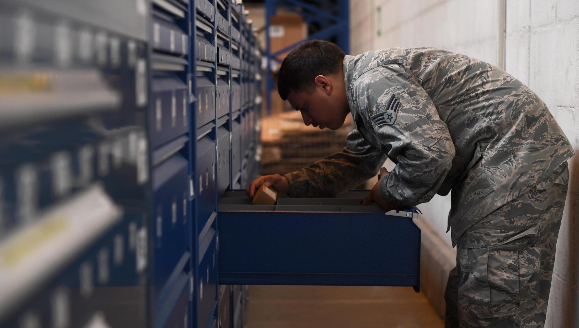 U.S. Air Force Senior Airman Julio Bonilla-Rodriguez, aircraft parts store journeyman assigned to 447th Air Expeditionary Group, grabs an ordered aircraft part from a drawer store at Incirlik Air Base, Turkey, Sept. 21, 2017. Additionally, APS provides life-saving improved outer tactical vests and enhanced small arms protective inserts to deployed personnel. (U.S. Air Force photo by Senior Airman Jasmonet D. Jackson)