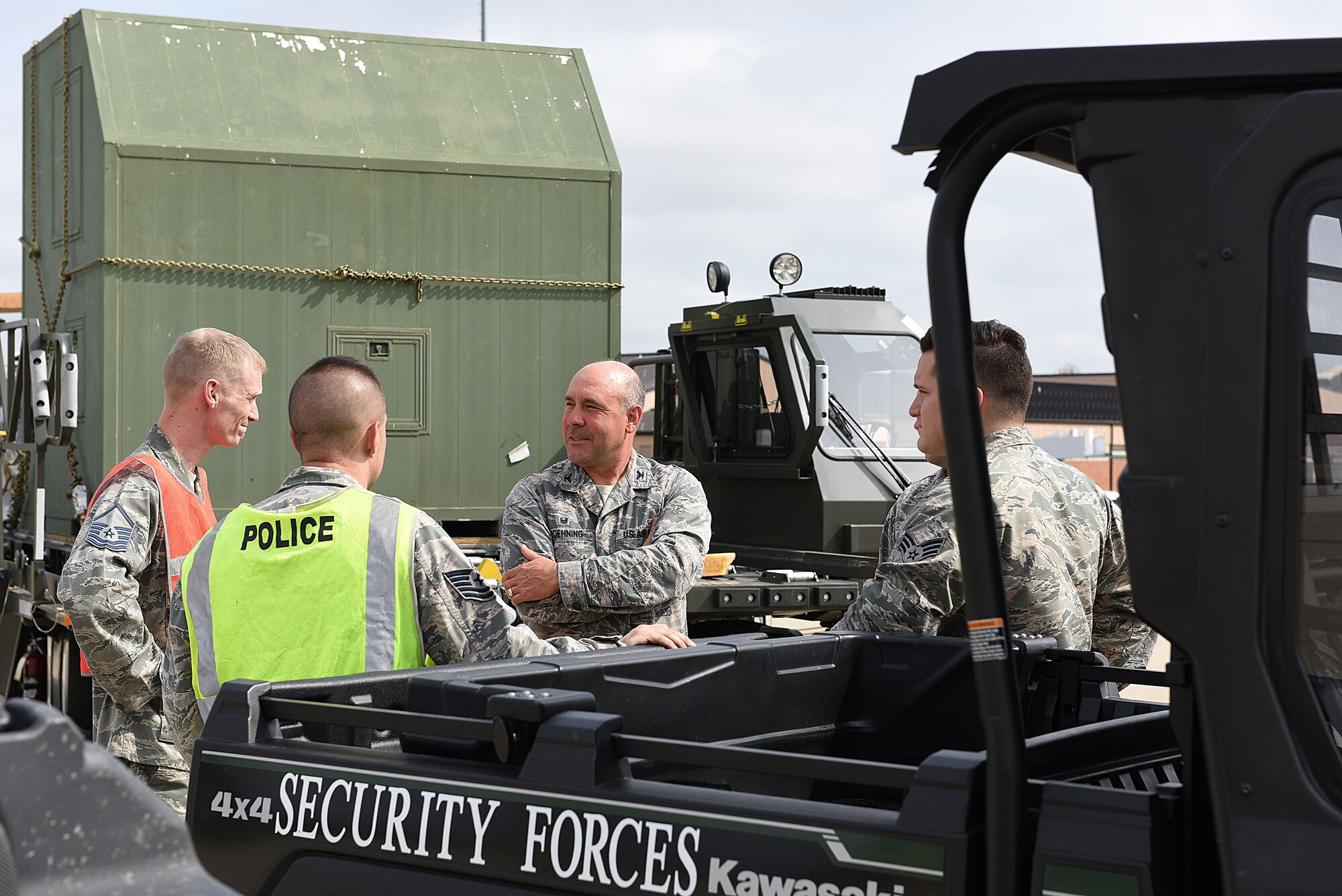 Col. Jonathan Boehning stands beside cargo pallets and all terrain vehicles talking to Security Forces personnel