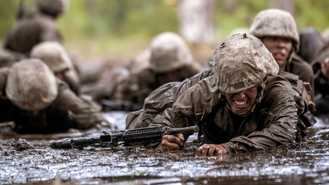 Marine recruits crawl through mud.