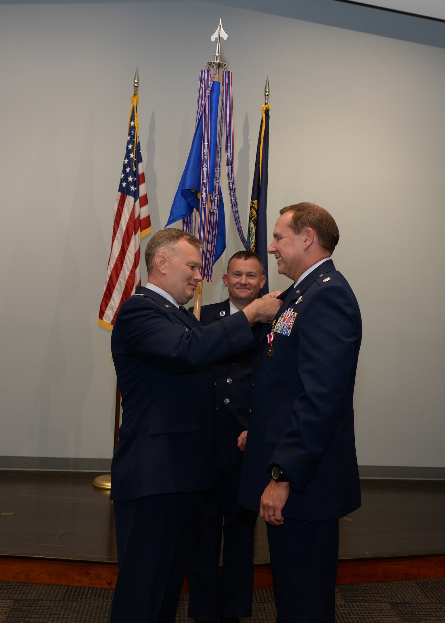 Col. John Pogorek, commander of the 157th Operations Group, left, pins a commander's pin on Lt. Col. Mark Ustaszewski, incoming commander of the 157th Operations Support Squadron during a change command ceremony as Master Sgt. Jason Veziris holds the 157th OSS unit guidon, Oct. 14, 2017,  Pease Air National Guard Base, N.H. Lt. Col. Ustaszewski replaces outgoing 157th OSS commander Lt. Col. Jeffery Cole, who served as the commander for two years and will be the new deputy commander for the 157th OG. (N.H. Air National Guard photo by Airman Victoria Nelson)