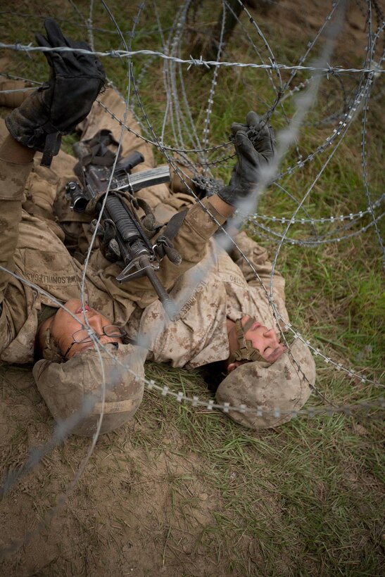 Recruits crawl under a wire as part of the obstacle course.