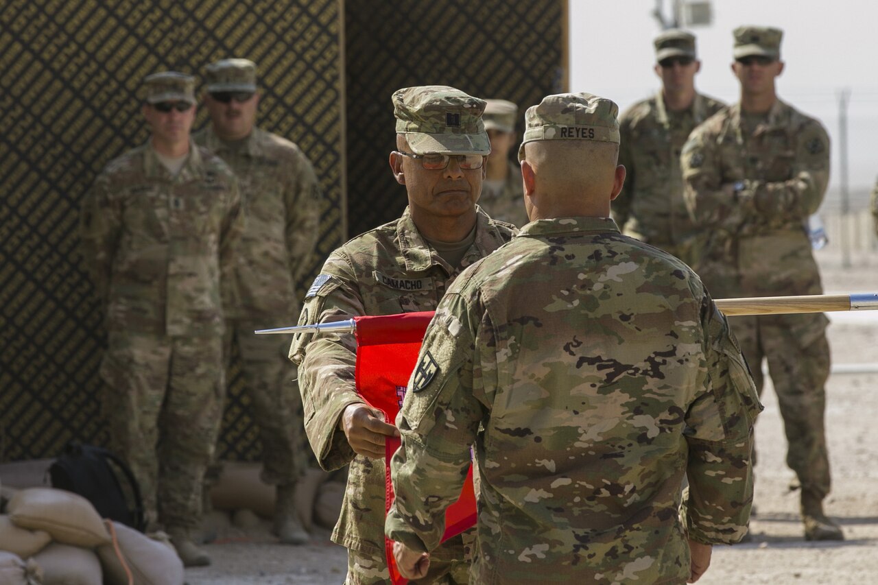 Army Capt. Luis Camacho Santiago and 1st Sgt. Jose Reyes case the colors of the Puerto Rico Army National Guard’s 215th Engineer Company during a transfer of authority ceremony at Camp Buehring, Kuwait.