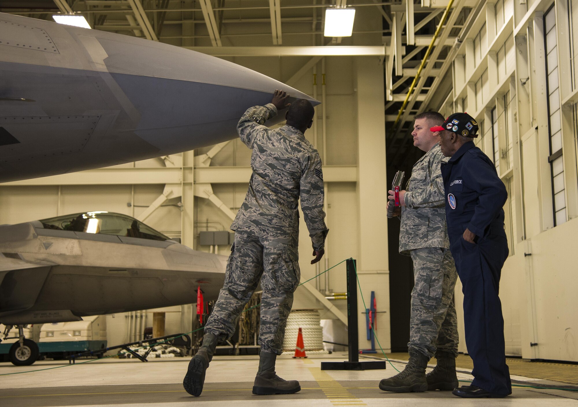 U.S. Air Force Staff Sgt. Stephen Teamer, 477th Aircraft Maintenance Squadron crew chief, demonstrates his knowledge of F-22 Raptors to Army Air Corps Staff Sgt. Leslie Edwards, a Tuskegee Airman of the 477th Bombardment Group, and U.S. Air Force Tech. Sgt. Jeremiah Frye, 477th Fighter Group quality assurance inspector, at Joint Base Elmendorf-Richardson, Alaska, Oct. 14, 2017.  Edwards accompanied Frye for his 5,000th quality assurance inspection, a milestone he reached in nine years which typically takes 28 years to accomplish. (U.S. Air Force photo by Senior Airman Curt Beach)
