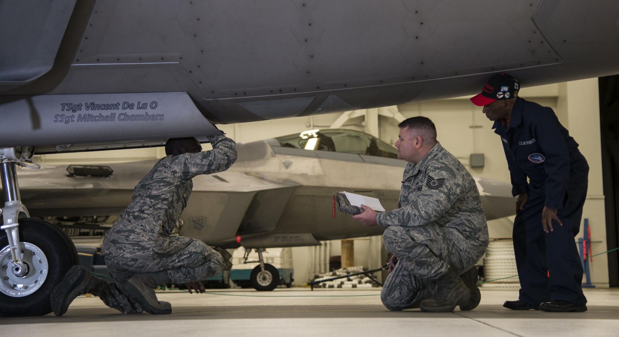 U.S. Air Force Staff Sgt. Stephen Teamer, 477th Aircraft Maintenance Squadron crew chief, demonstrates his knowledge of F-22 Raptors to U.S. Air Force Tech. Sgt. Jeremiah Frye, 477th Fighter Group quality assurance inspector, and Army Air Corps Staff Sgt. Leslie Edwards, the last known living Tuskegee Airman of the 477th Bombardment Group, at Joint Base Elmendorf-Richardson, Alaska, Oct. 14, 2017. Edwards accompanied Frye for his 5,000th quality assurance inspection, a milestone he reached in nine years which typically takes 28 years to accomplish. In 2007, the 477th Bombardment Group became the 477th Fighter Group, bringing with it the legacy of Tuskegee Airmen to Alaska. (U.S. Air Force photo by Senior Airman Curt Beach)