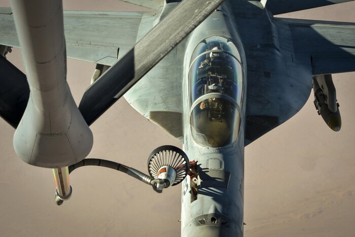 A plane in flight receives fuel from the boom of another aircraft flying above it.