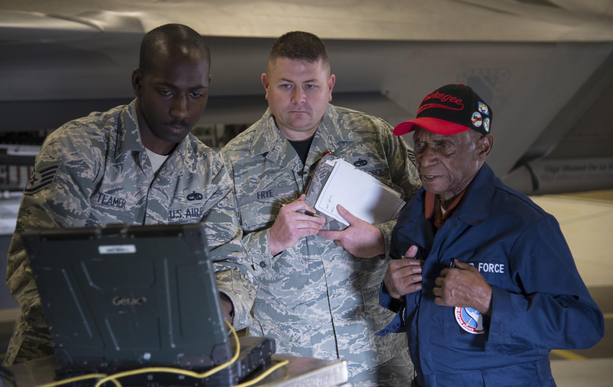U.S. Air Force Staff Sgt. Stephen Teamer, 477th Aircraft Maintenance Squadron crew chief, operates a portable maintenance aid during a quality insurance inspection with Army Air Corps Staff Sgt. Leslie Edwards, a Tuskegee Airman of the 477th Bombardment Group, and Tech. Sgt. Jeremiah Frye, 477th FG quality assurance inspector, at Joint Base Elmendorf-Richardson, Alaska, Oct. 14, 2017. Edwards accompanied Frye for his 5,000th quality assurance inspection, a milestone he reached in nine years which typically takes 28 years to accomplish. In 2007, the 477th Bombardment Group became the 477th Fighter Group, bringing with it the legacy of Tuskegee Airmen to Alaska. (U.S. Air Force photo by Senior Airman Curt Beach)