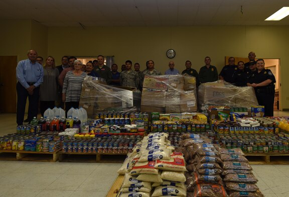 Federal agency members pose in the Val Verde Loaves and Fishes warehouse behind the food Laughlin Air Force Base, Texas donated and unloaded at the Feds Feed Families event in Del Rio, Texas, Oct. 11, 2017. (U.S. Air Force photo/Airman 1st Class Anne McCready)