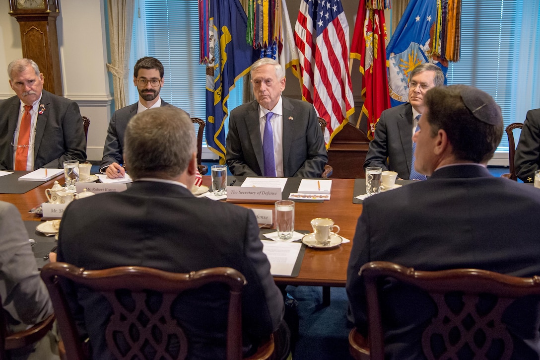 Defense Secretary Jim Mattis sits at a table with a group of people.