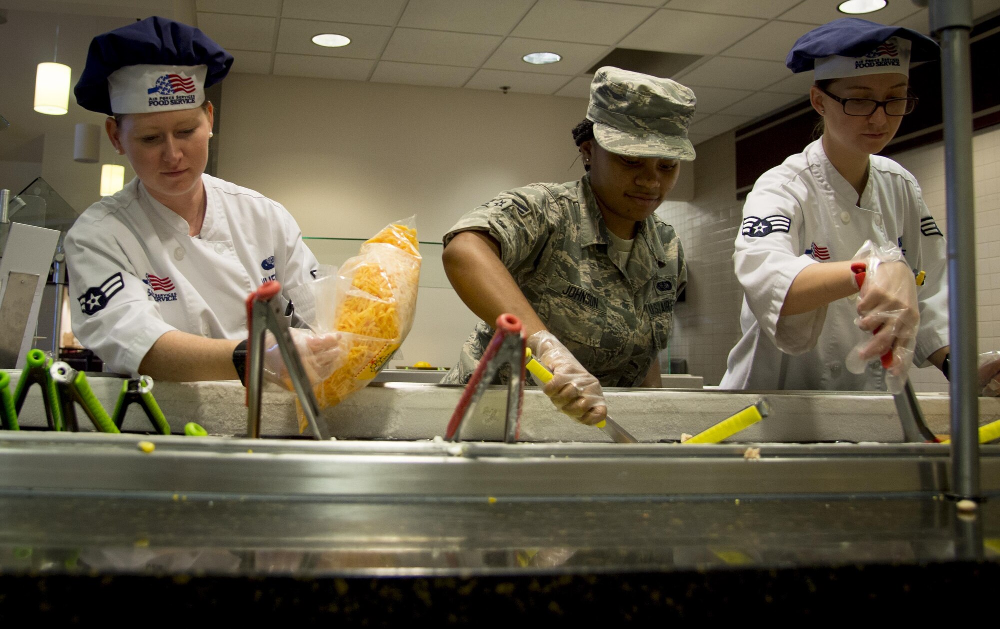 U.S. Air Force Airman 1st Class Kaeleigh Mueller, left, services journeymen, Airman 1st Class Chyna Johnson, center, a services apprentice, and Senior Airman Brandy Schaff, right, a services journeymen, all assigned to the 6th Force Support Squadron, restock the salad bar during lunch in the dining facility at MacDill Air Force Base, Fla., Oct. 19, 2017. The MacDill dining facility provides various food options to their customers including a salad bar, to-go items and hot food selections. (U.S. Air Force photo by Senior Airman Mariette Adams)