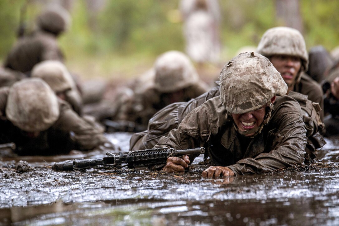 Marine recruits crawl through mud.