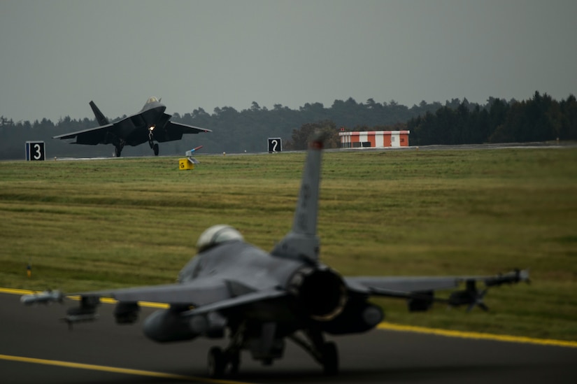 An F-22 Raptor assigned to the 1st Fighter Wing, Joint Base Langley-Eustis, Va., lands while an F-16 Fighting Falcon assigned to the 480th Fighter Squadron taxis at Spangdahlem Air Base, Germany, Oct. 13, 2017.