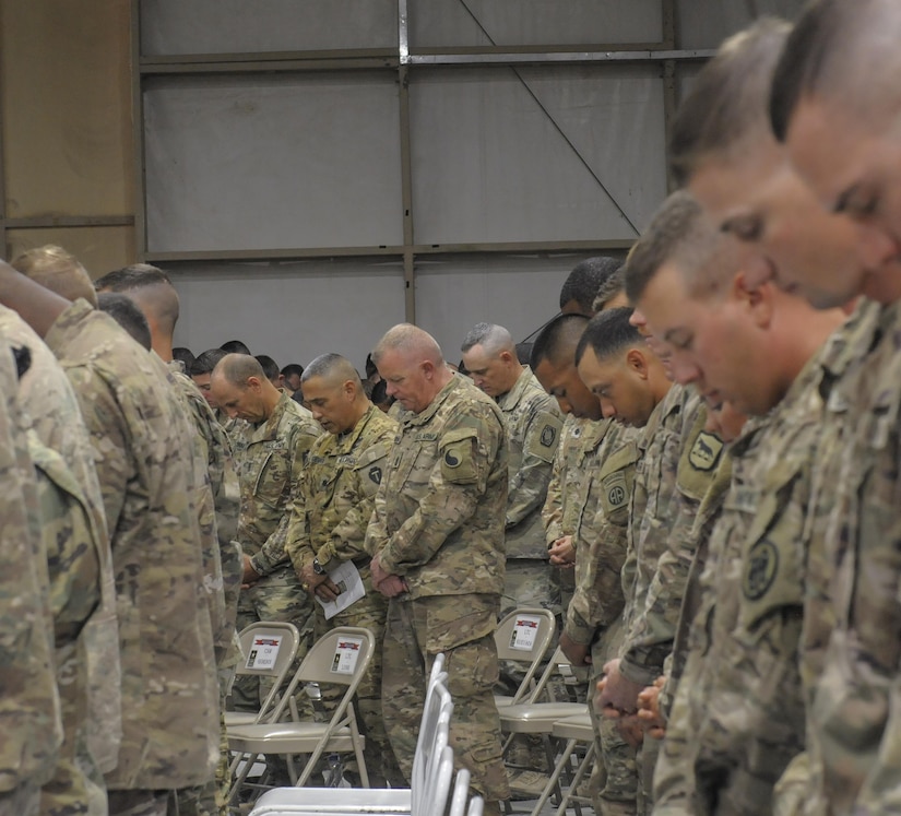 Soldiers bow their heads during a prayer.