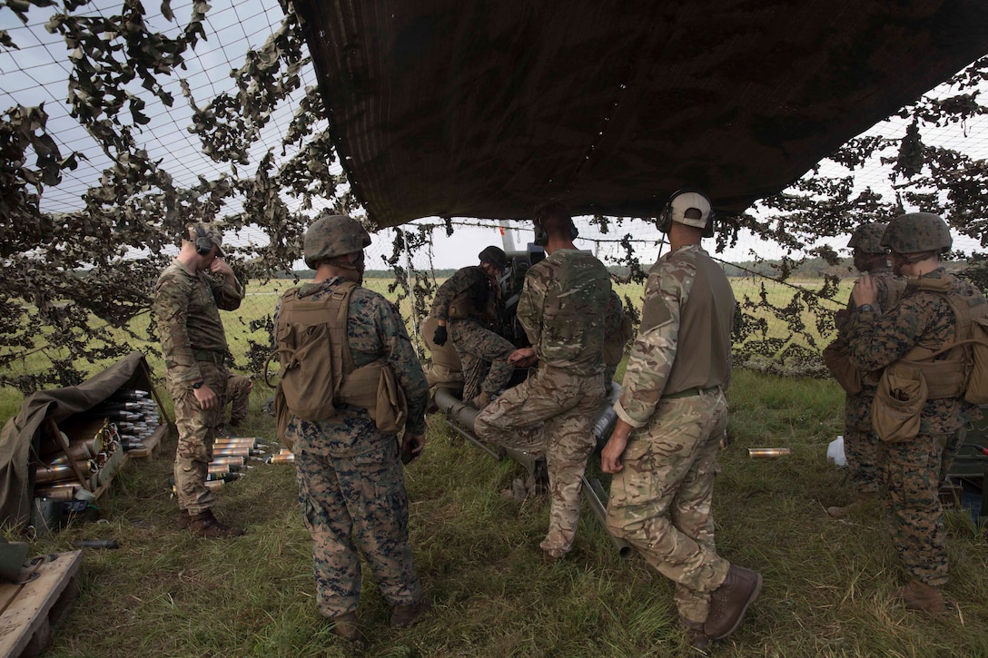 A Marine field artillery cannoneer and British commando gunners prepare to fire an M119A3 Howitzer during field artillery training at Camp Lejeune, N.C., Oct. 11, 2017. British soldiers exchanged knowledge and skills with U.S. Marines to refine their artillery operation capabilities in preparation for joint exercise Bold Alligator, a large-scale, multinational Naval amphibious exercise to execute complex shaping, amphibious, and sea basing operations to improve U.S. and coalition ship-to-shore capabilities. The Marines are with 2nd Battalion, 10th Marine Regiment and the British soldiers are with 29 Commando Regiment, Royal Artillery. (U.S. Marine Corps photo by Pfc. Nicholas Guevara)